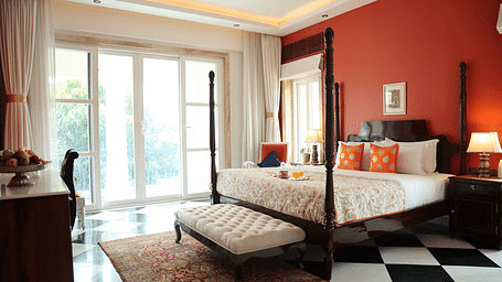 A room at Dileep Kothi, Jaipur with a double bed, side tables with night lamps, French windows and checker-ed tiles